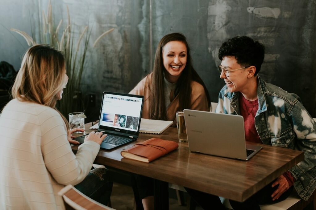 Three students learning together around a laptop during a training session